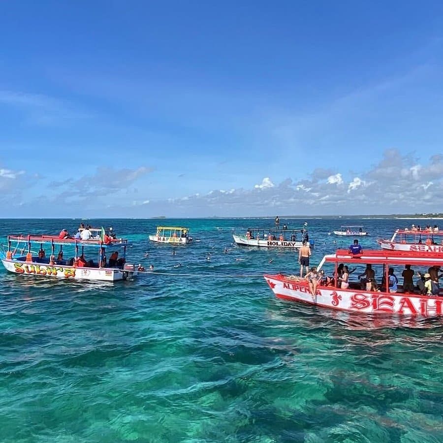 A group of travelers gathered on a white sandbar surrounded by turquoise water
