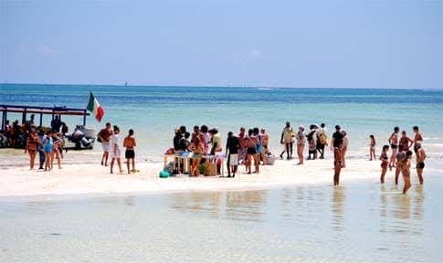 A couple in snorkeling gear standing on a sandbar in the clear Indian Ocean shallows