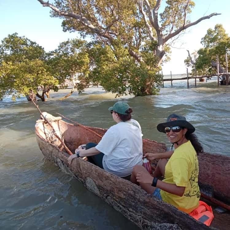 Travelers smiling aboard a traditional dugout canoe on a mangrove lagoon
